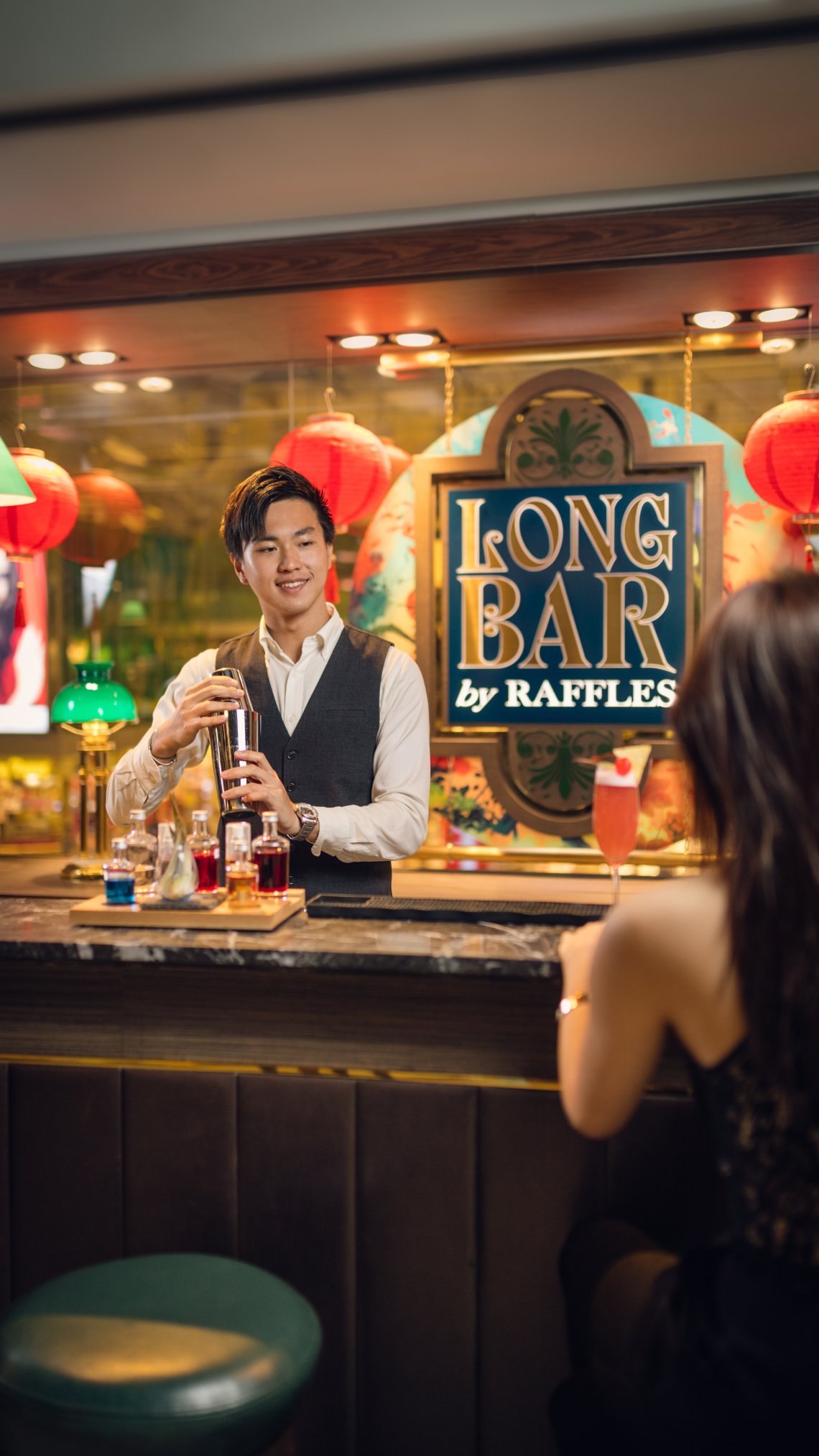 A bartender shaking a cocktail for a customer